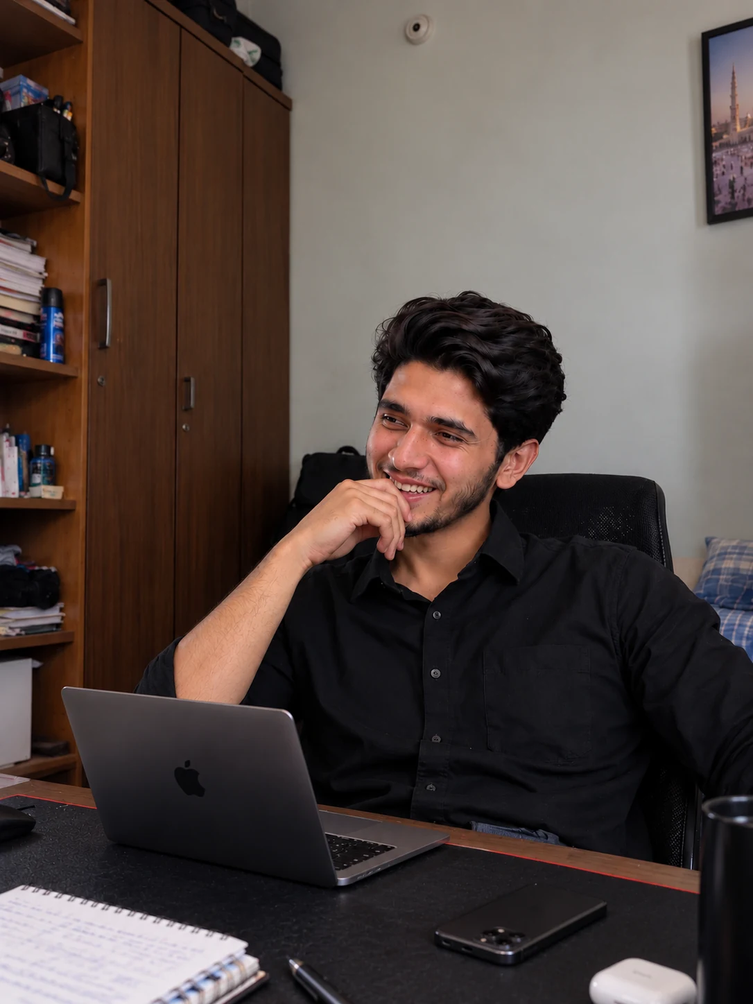 Afnan Javed smiling naturally while seated at his workspace